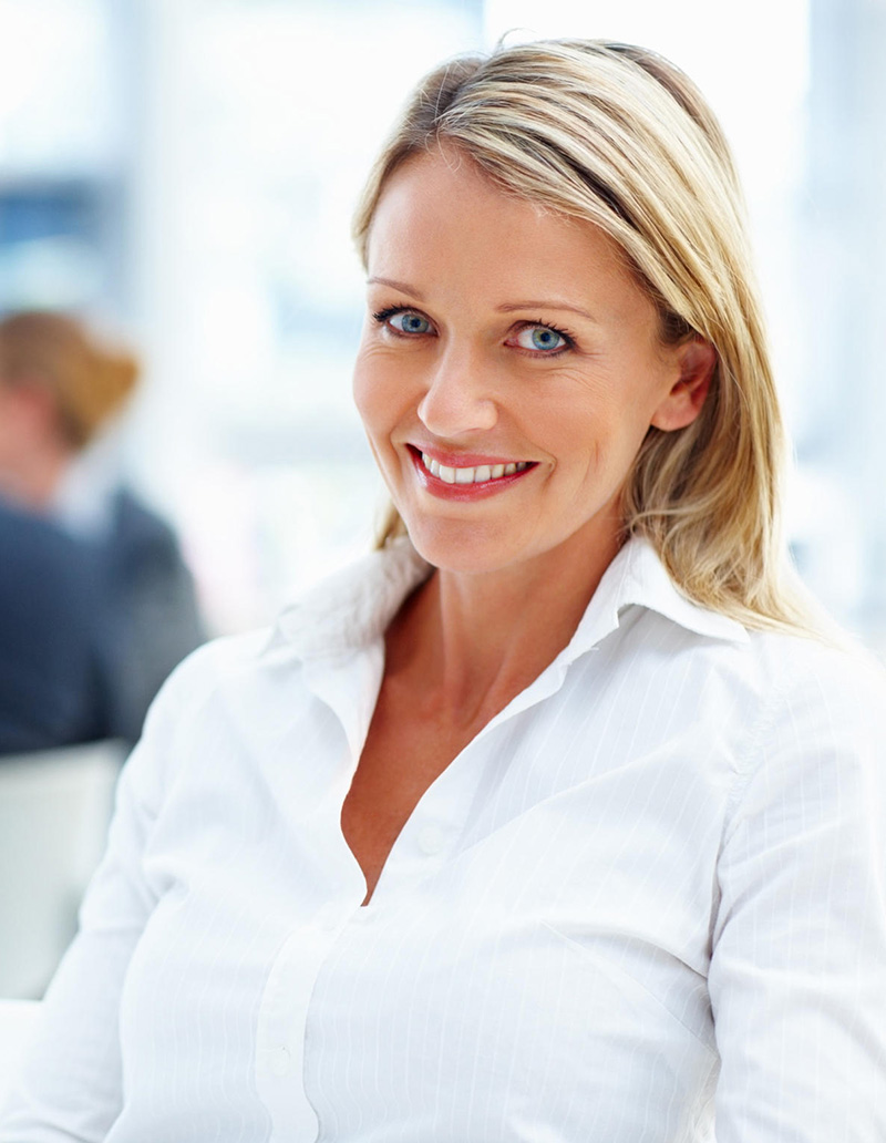 A professional business woman sitting in office with coworkers working in the background